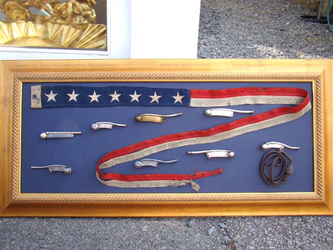 A framed collection of 8 bosuns' whistles and a ships pennant
